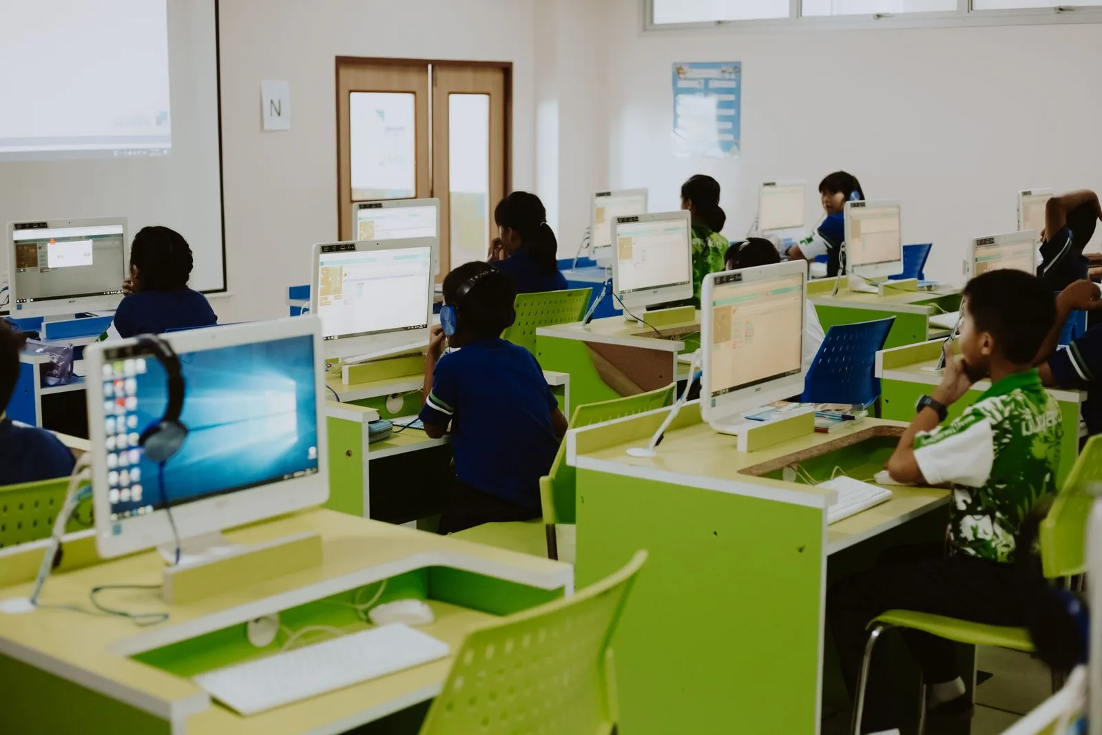 A school computer lab full of children learning block-based coding