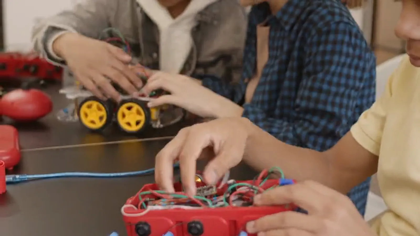 Students assembling wired robot cars at the workshop table