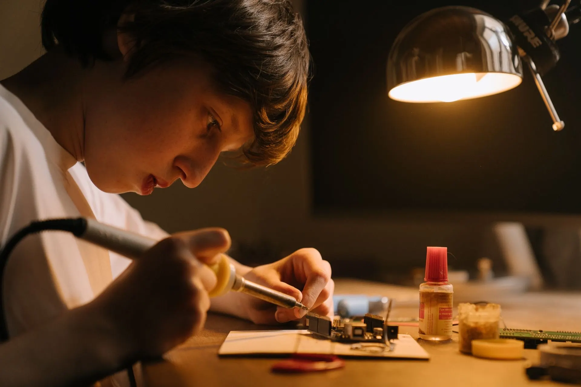 A child building at a glowing screen in a dim room