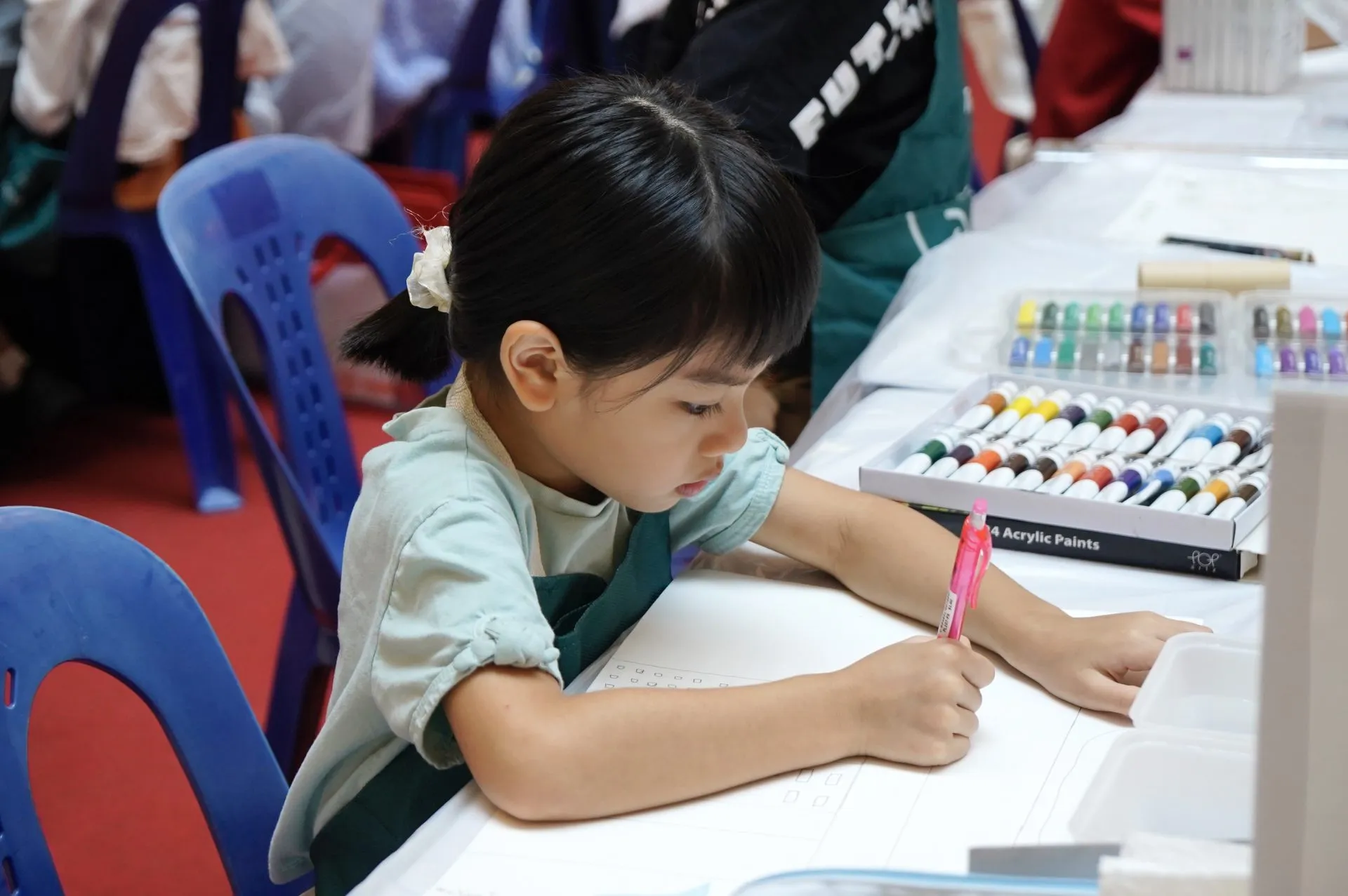A young OpenKids art student concentrating on her painting