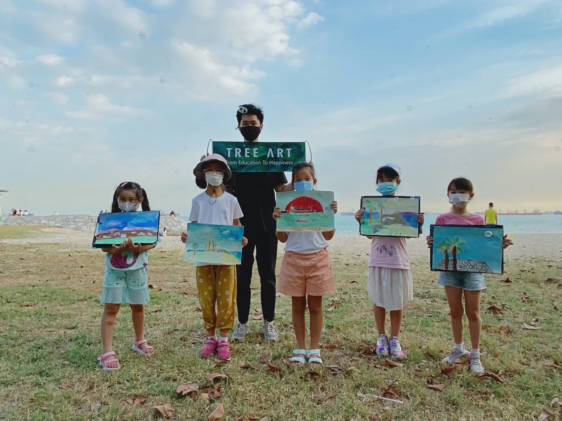 OpenKids art students painting outdoors by the sea with their instructor