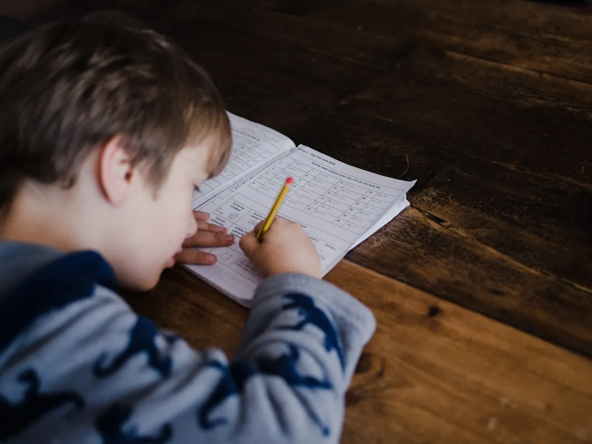 A boy concentrating on his writing practice at a desk